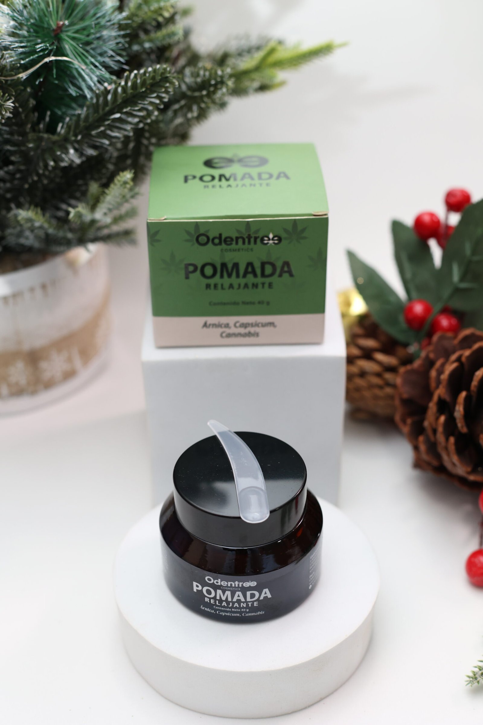 Persona sosteniendo la pomada Odentree de CBD y cáñamo en un entorno navideño